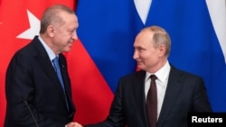 Russian President Vladimir Putin and Turkish President Tayyip Erdogan shake hands during a news conference following their talks in Moscow, Russia, March 5, 2020. 