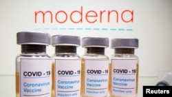 Vials with a sticker reading, "COVID-19 / Coronavirus vaccine / Injection only" and a medical syringe are seen in front of a displayed Moderna logo in this illustration taken October 31, 2020. REUTERS/Dado Ruvic/Illustration