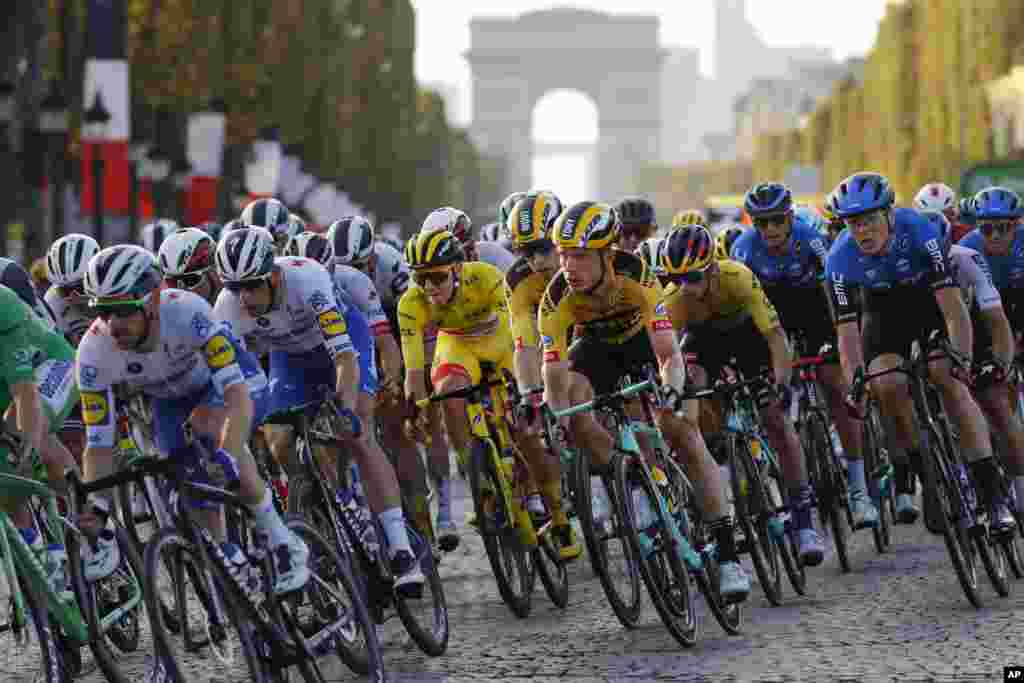 Slovenia's Tadej Pogacar, wearing the overall leader's yellow jersey, center, rides down Champs Elysees with the pack during the twenty-first and last stage of the Tour de France cycling race over 122 kilometers (75.8 miles), from Mantes-la-Jolie to Paris, France.