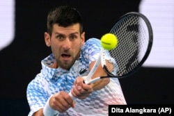 Novak Djokovic of Serbia plays a backhand return to Stefanos Tsitsipas of Greece during the men's singles final at the Australian Open tennis championship in Melbourne, Australia, Sunday, Jan. 29, 2023. (AP Photo/Dita Alangkara)