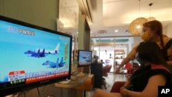 台北一家美髮廳的顧客和理髮師在觀看電視報導的中國針對台灣的軍演。（2022年8月4日）