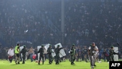 This picture taken on October 1, 2022 shows members of the Indonesian army securing the pitch after a football match between Arema FC and Persebaya Surabaya at Kanjuruhan stadium in Malang, East Java.