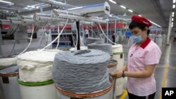 资料照片：在中国政府组织的外国记者参观期间，工人在位于新疆维吾尔自治区阿克苏的华孚时尚工厂内作业。(2021年4月20日)