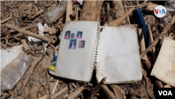 Fotos familiares pegadas en un cuaderno están tiradas entre ramas secas y lodo.