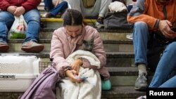A woman with a cat shelters inside a subway station during a Russian missile attack in Kyiv, Ukraine, Oct. 11, 2022.
