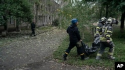 Ukrajinske spasilačke ekipe odnose tijelo žene poslije ruskog napada na školu u oblasti Luganska, 28. septembar 2022.