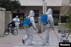 身穿防护服的防疫人员在北京一个被封的居民区喷洒消毒药水。（2022年11月9日）