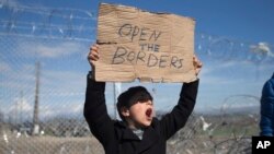 Dečak na grčkoj strani granice sa Makedonijom drži natpis na kojem piše "Otvorite granice", 27. februar 2016.