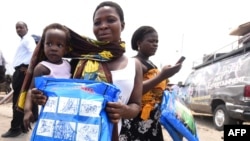 A woman carrying a baby holds a treated mosquito net during a malaria prevention event in Lagos, Nigeria, April 2016. (AFP Photo)