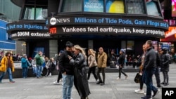 La gente camina por Times Square mientras los teletipos muestran noticias sobre el terremoto del 5 de abril de 2024 en Nueva York.