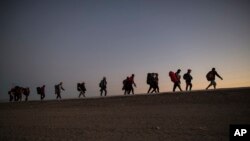 ARCHIVO - Migrantes centroamericanos caminan al final de la tarde cuando salen de Mexicali, México, el 20 de noviembre de 2018, en camino a Tijuana.