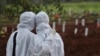 Des membres de la famille regardent des ouvriers enterrer un cercueil dans la section spéciale du cimetière de Padurenan qui a été ouverte pour faire face à l'augmentation des décès dû à l'épidémie de coronavirus à Bekasi, en Indonésie, jeudi 17 juin 2021.
