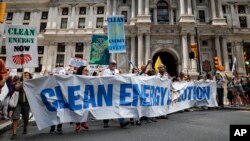 Climate change activists carry signs as they march during a protest in downtown Philadelphia ahead of the Democratic National Convention, July 24, 2016.