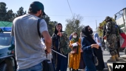 FILE - A Taliban member cracks down on journalists covering a women's rights protest in Kabul, Oct. 21, 2021.