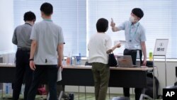 Employees of the beverage maker Suntory register to receive shots of the Moderna COVID-19 vaccine at their office building as the company began its workplace vaccination Monday, June 21, 2021, in Tokyo. Thousands of Japanese companies began…