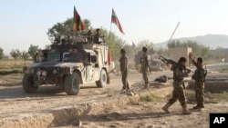 Afghan national army stand guard near the dead body of a Taliban attacker in front of the main prison building after an attack in Ghazni province, eastern Afghanistan, Monday, Sept. 14, 2015.