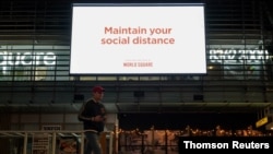 A man walks under a public health message about social distancing displayed at a shopping plaza in the city center during a lockdown to curb the spread of a coronavirus disease (COVID-19) outbreak in Sydney, July 6, 2021.