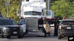 San Antonio police officers investigate the scene where eight people were found dead in a tractor-trailer loaded with at least 30 others outside a Walmart store in stifling summer heat in what police are calling a horrific human trafficking case, Sunday, July 23, 2017, in San Antonio. 