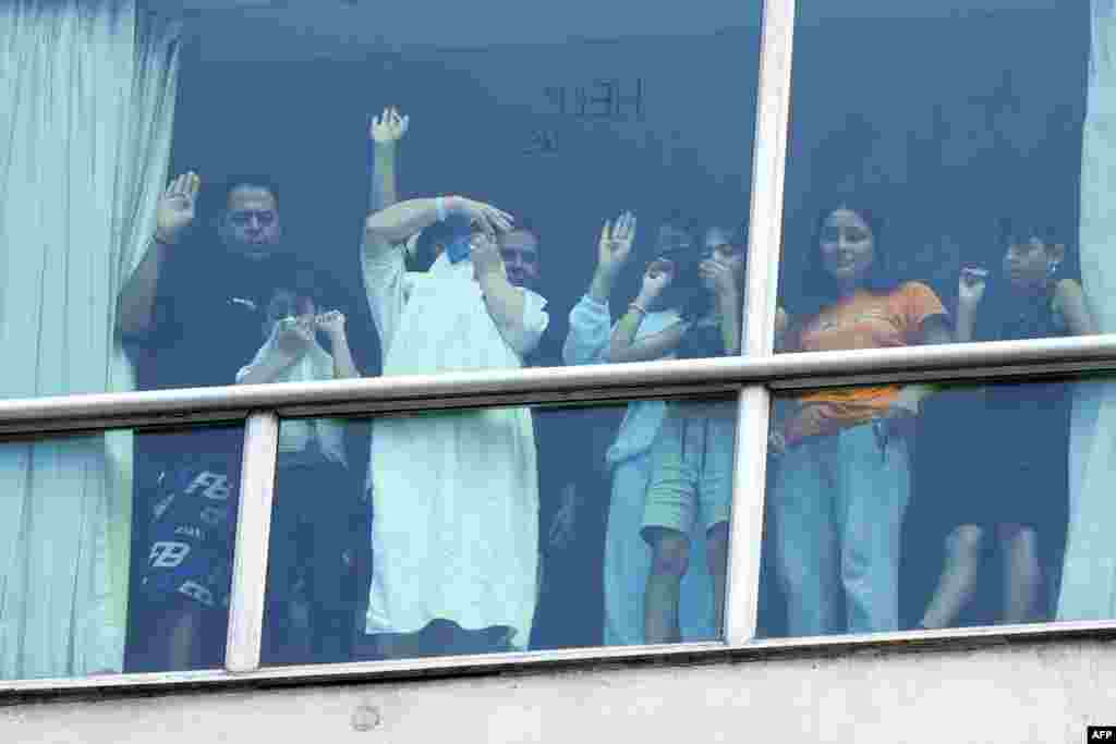 Migrants deported from the U.S. gesture as they look out the window of the Decapolis Hotel where they are temporarily staying in Panama City, Feb. 18, 2024.&nbsp;Panama's government denied&nbsp; that migrants deported by the United States who were seen holding up signs to hotel windows pleading for help were being held against their will.