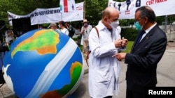 Un miembro de Médicos por XR habla con el director general de la OMS, Tedros Adhanom Ghebreyesus, durante una manifestación exigiendo medidas sobre el cambio climático, en Ginebra, Suiza, el 29 de mayo de 2021.