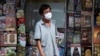 Un homme portant un masque facial pour aider à freiner la propagation du nouveau coronavirus se tient devant une librairie à Bangkok, en Thaïlande, le mardi 26 mai 2020. (AP Photo/Sakchai Lalit)