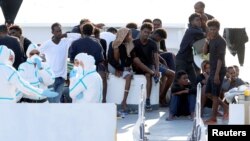 FILE - Migrants wait to disembark from the Italian coast guard vessel "Diciotti" at the port of Catania, Italy, Aug. 22, 2018.