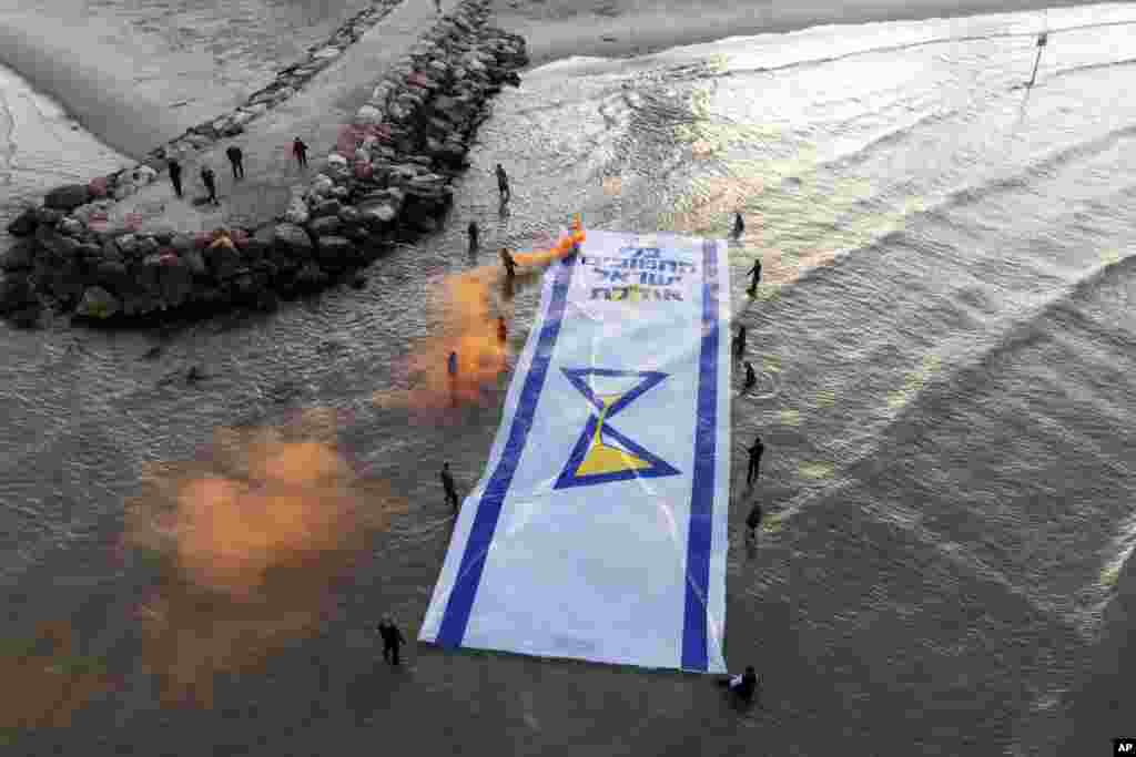 Relatives and supporters of Israelis held hostage by Hamas in Gaza mark 500 days of their captivity by spreading a massive Israeli flag depicting an hourglass in the Mediterranean Sea, in Tel Aviv.&nbsp;Hebrew of the flag reads "Without the abductees, Israel runs out."