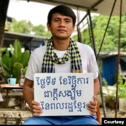 រូបឯកសារ៖ លោក ឈុន វាន សកម្មជន​គណបក្ស​សង្រ្គោះ​ជាតិ ដែល​ត្រូវ​បាន​តាម​ចាប់​ខ្លួន កាន់បដា​ដែល​សរសេរ​ថា «ថ្ងៃទី៩ វិច្ឆិកា ជាក្តីសង្ឃឹម​របស់​ពលរដ្ឋ​ខ្មែរ»។