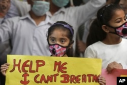 An Indian girls holds a banner during a protest against air pollution in New Delhi, India, Nov. 6, 2016.