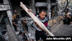 Wakazi wa Gaza wakikusanya baadhi ya mali zao kutoka vifusi vya jengo la Al-Jawhara lililobomolewa na makombora ya Israel