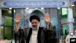 Ebrahim Raisi, a candidate in Iran's presidential elections, raises his hands as he casts his vote at a polling station in Tehran, Iran, June 18, 2021.