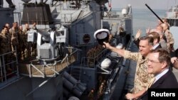 FILE: German Defense Minister Jung, right, and Captain Kay-Achim Schoenbach, second right, wave as the German navy frigate Karlsruhe sails out of the harbor in Djibouti. 