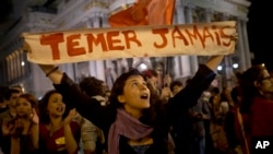 Una mujer levanta una pancarta que dice en portugués "Nunca Temer" en protesta contra el gobierno interino de Michel Temer en mayo de 2016. Desde su inicio, el mandatario enfrenta retos que amenazan su posible permanencia en el poder.