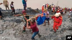 រូបថតដោយមន្ទីរពន្លត់អគ្គីភ័យមីយ៉ាន់ម៉ា បង្ហាញក្រុមអ្នកជួយសង្គ្រោះកំពុងលីសាកសពជនរងគ្រោះដោយសារឧប្បទ្ទវហេតុបាក់ដីនៅកន្លែង​ជីក​យក​រ៉ែ​ថ្លើម​ថ្ម​មួយ​កន្លែង​នៅតំបន់ Hpakant (ផាកាន់ថ៍) នៃ​រដ្ឋ Kachin នៅថ្ងៃទី២ ខែកក្កដា ឆ្នាំ២០២០។ (រូបថតដោយមន្ទីរពន្លត់អគ្គីភ័យមីយ៉ាន់ម៉ា via AP)