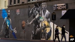 Pešaci sa maskama za lice na Holivudskom bulevaru u Los Anđelesu 24. marta 2020. (Foto: AP Photo/Damian Dovarganes)