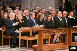 จากซ้ายไปขวา: แถวหน้า - รองปธน.คามาลา แฮร์ริส และสุภาพบุรุษหมายเลขสอง ดัก เอ็มฮอฟฟ์ / แถวสอง - อดีตปธน.บิลล์ คลินตัน, อดีตรมว.ตปท.ฮิลลารี คลินตัน, อดีตปธน.จอร์จ ดับเบิลยู บุช และอดีตสุภาพสตรีหมายเลขหนึ่ง ลอรา บุช, อดีตปธน.บารัค โอบามา, ว่าที่ปธน.โดนัลด์ ทรัมป์และเมลาเนีย ทรัมป์