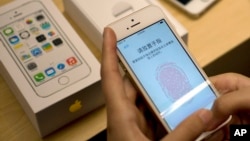 In this Sept. 20, 2013 file photo, a customer configures the fingerprint scanner technology built into the Apple iPhone 5S at an Apple store in Wangfujing shopping district in Beijing, China. (AP Photo/Andy Wong, File)