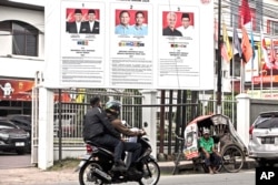 Seorang tukang becak menunggu pelanggan di dekat spanduk pemilihan calon presiden di Medan, 13 Februari 2024. (Foto: AP)