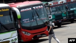 En la foto de archivo se ve a un hombre corriendo para tomar una unidad de transporte en El Salvador.