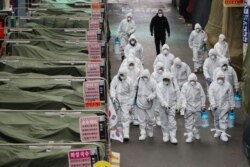 Market workers wearing protective gear spray disinfectant at a market in the southeastern city of Daegu on February 23, 2020 as a preventive measure after the COVID-19 coronavirus outbreak.