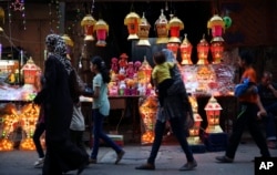 Palestinians walk in front of traditional lighted Ramadan lanterns, marking the holy month of Ramadan at main market in Gaza City, June 3, 2016.