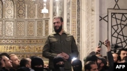 2024年12月8日，伊斯蘭主義組織沙姆解放組織領導人阿布·穆罕默德·朱拉尼在大馬士革著名的倭馬亞大清真寺對人群講話。朱拉尼已開始使用他的真名艾哈邁德·沙拉。