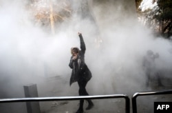 An Iranian woman raises her fist amid the smoke of tear gas at the University of Tehran during a protest, in Tehran, Iran, Dec. 30, 2017.