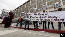 Members of a group calling itself Refuse Fascism protest the Tuesday firing of FBI director James Comey by President Donald Trump, outside the downtown Los Angeles federal building, May 10, 2017.