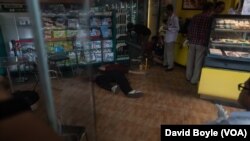FILE - Police survey the crime scene where Kem Ley was shot dead while family members pray next to his dead body, July 10, 2016.