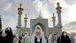 Worshippers wearing protective face masks offer Eid al-Fitr prayers outside a shrine to help prevent the spread of the coronavirus, in Tehran, Iran, Sunday, May 24, 2020