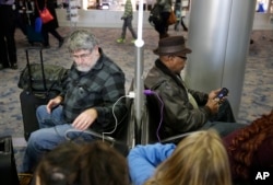 In this Dec. 29, 2014, photo, people use a charging station at McCarran International Airport in Las Vegas.