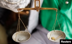 FILE - A trader weighs gold nuggets at a mine-pit in Walungu territory of South-Kivu province near Bukavu, Democratic Republic of Congo, April 5, 2014.