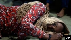 ፋይል ፎቶ - ከሊቢያ በሜዲተራንያን ባህር በኩል አልፈው ወደ አውርሮፓ ለመሻገር ሲሞክሩ በቤልጅግ የጦር ባህር መርከብ ነፍስ አድን ዘመቻ የዳኑ አንድ ፍልሰተኛ ኢታልያ ከገቡ በኋላ መርከቡ ውስጥ መሬት ላይ ባረፉበት ወቅት የተነሳ ፎቶ(አሶሽየትድ ፕረስ/AP Photo)