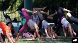 FILE - People perform yoga to mark International Yoga Day, in Milan, Wednesday, June 21, 2017. (AP Photo/Luca Bruno)